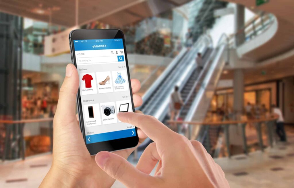 A person uses their smartphone to shop online at a mall.