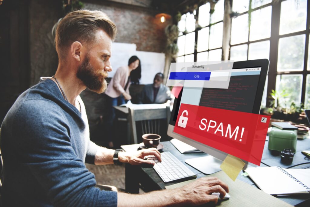 A man looks at his computer as he sees the word "SPAM!" written on it. He's trying to transfer data but it's stuck at 75%.